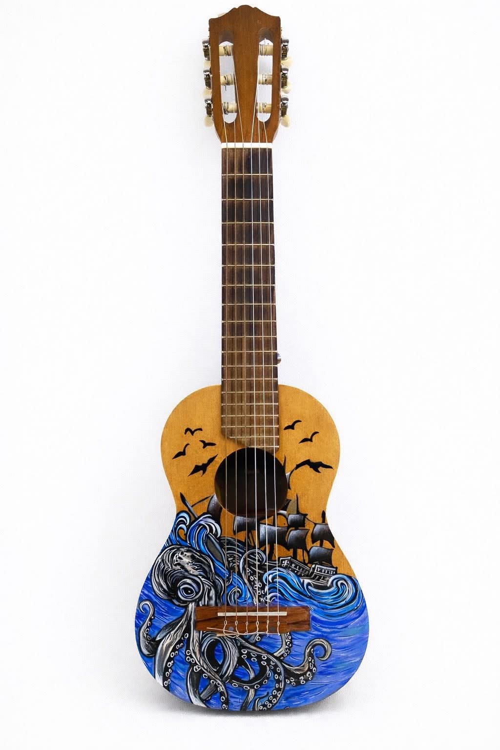 A hand-painted acoustic guitar with a unique design featuring an octopus and ship on a blue sea background, set against a ...