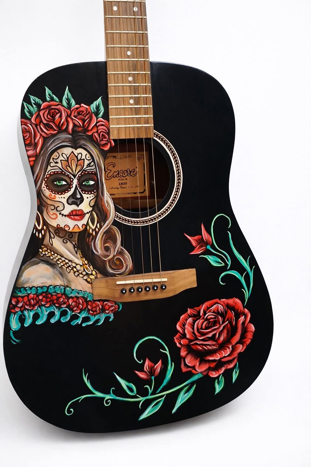 The image depicts a black guitar with a painted design on its body. The design features a woman's face adorned with sugar ...